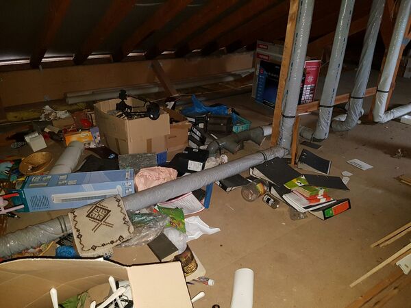 Dachboden mit herumliegendem Gerümpel, Kartons, Aktenordnern und Isolationsrohren.