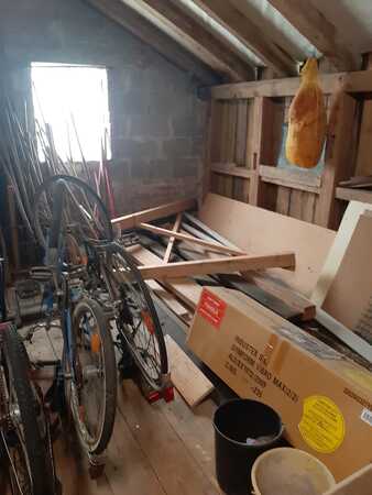 Dachboden mit alten Fahrrädern, Holzbalken, Kartons und aufgehängtem Schinken.