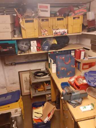 Kellerraum mit Regalen voller Werkzeug, Kisten, Aktenordnern und Bastelmaterial.