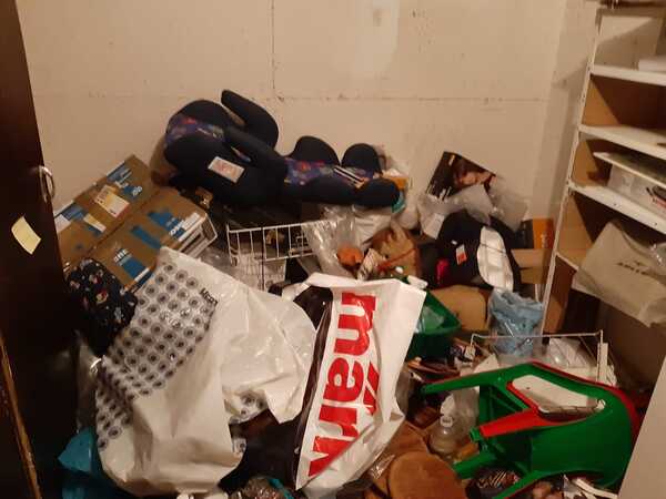 Überfüllter Kellerraum mit Kartons, Regalen, Plastiktüten und verschiedenen Haushaltsgegenständen.